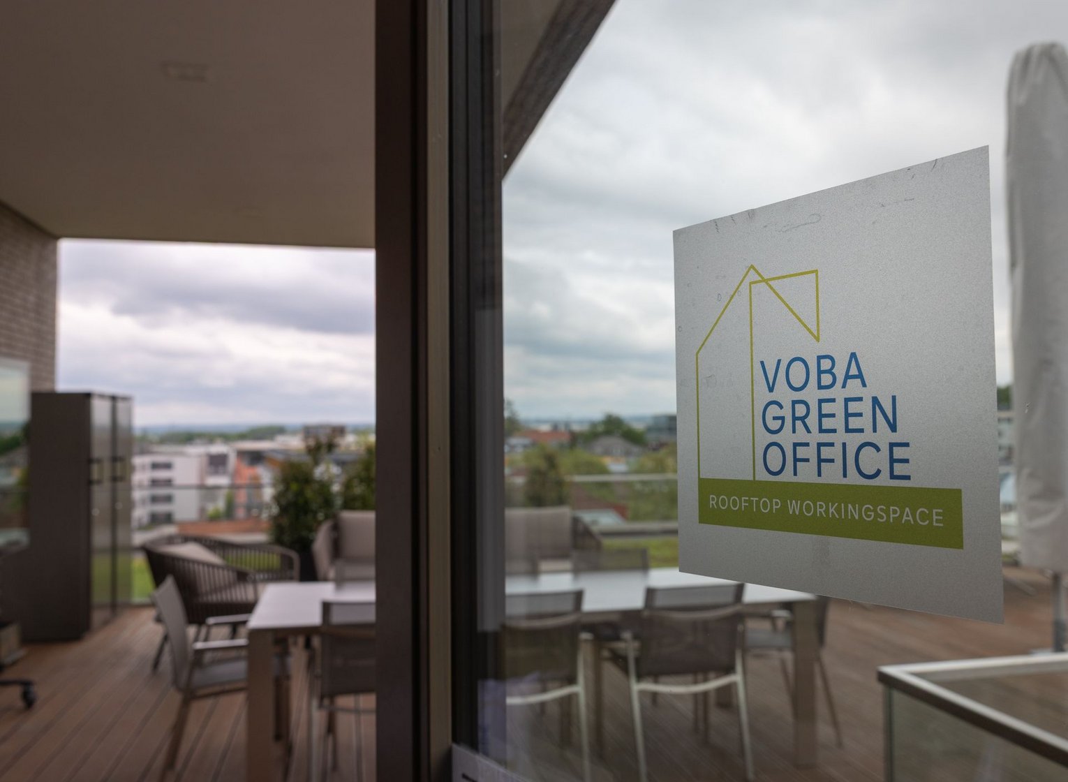 Blick auf die Dachterrasse unserer Volksbank, im VOrdergrund ein Aufkleber an der Scheibe mit "Voba Green Office"